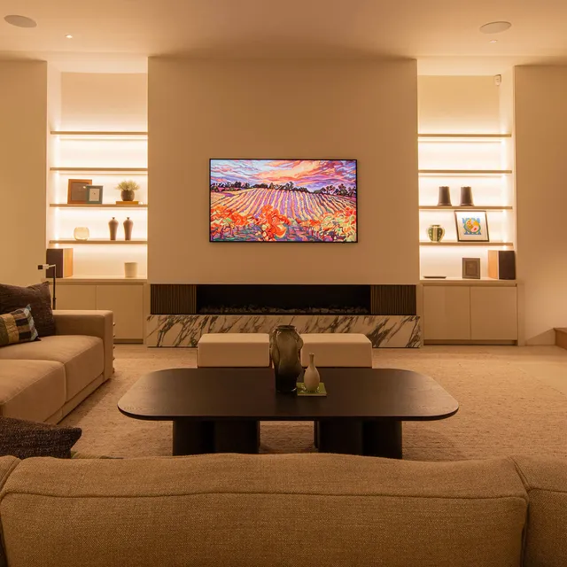 Brightly lit shelves flanking a Samsung The Frame TV in a clean modern living room