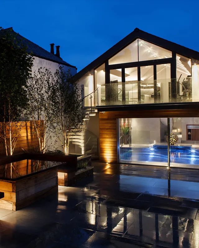 A private spa and pool complex at night with subtle garden lighting