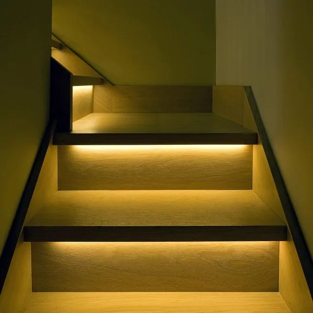 Recessed linear LED lighting under the treads of a wooden staircase